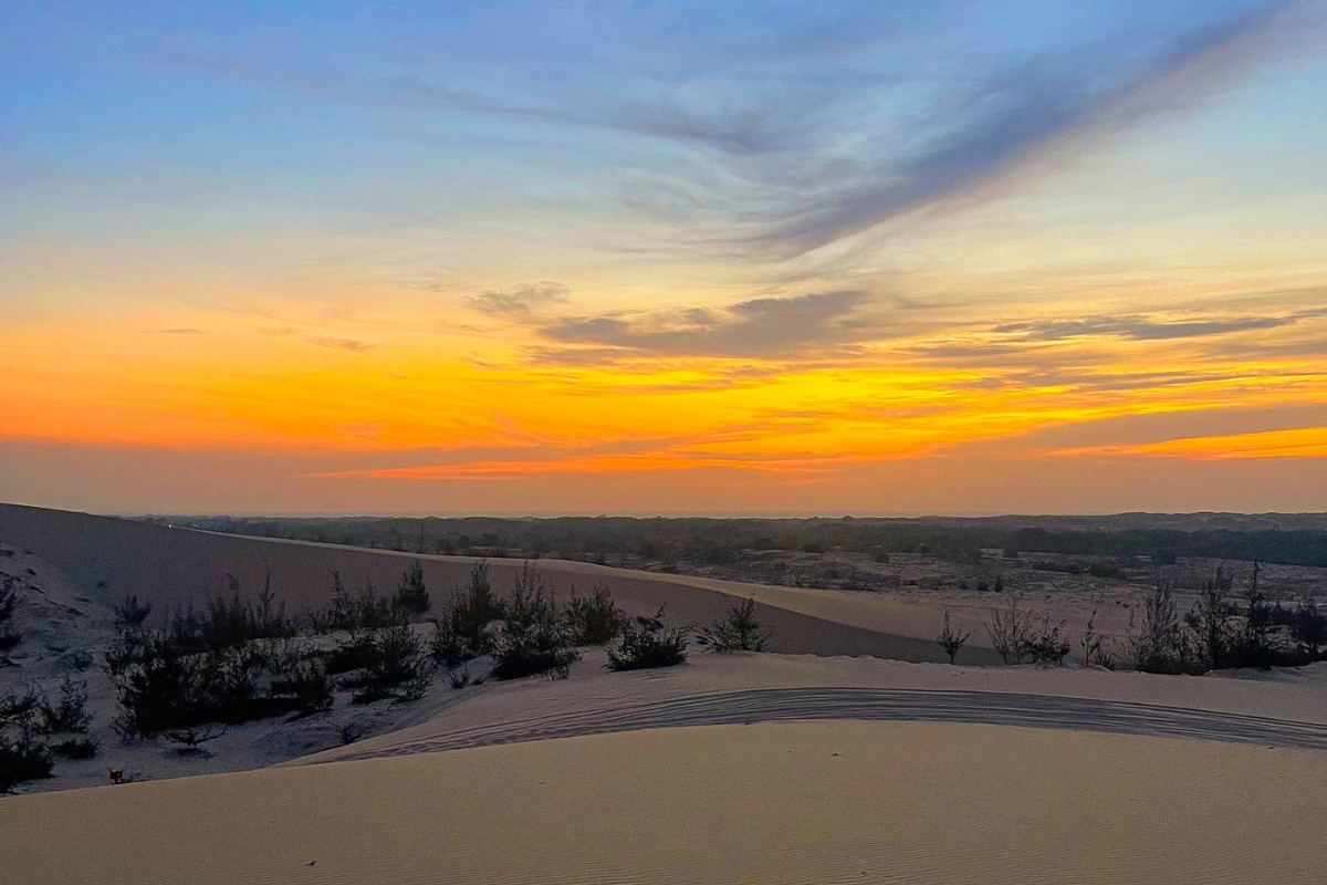 Sunset view over the white sand dunes with warm golden light and clear sky in Mui Ne